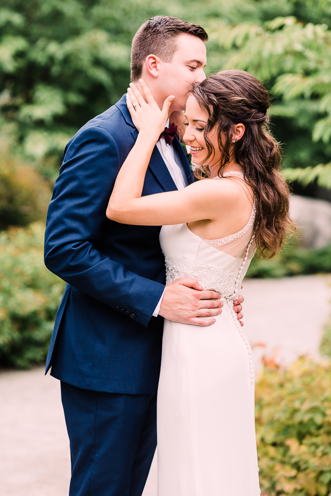 Bride and groom holding each other in navy suit smiling during first look at Fredrick Meijer Gardens by Grand Rapids wedding photographer Stephanie Anne