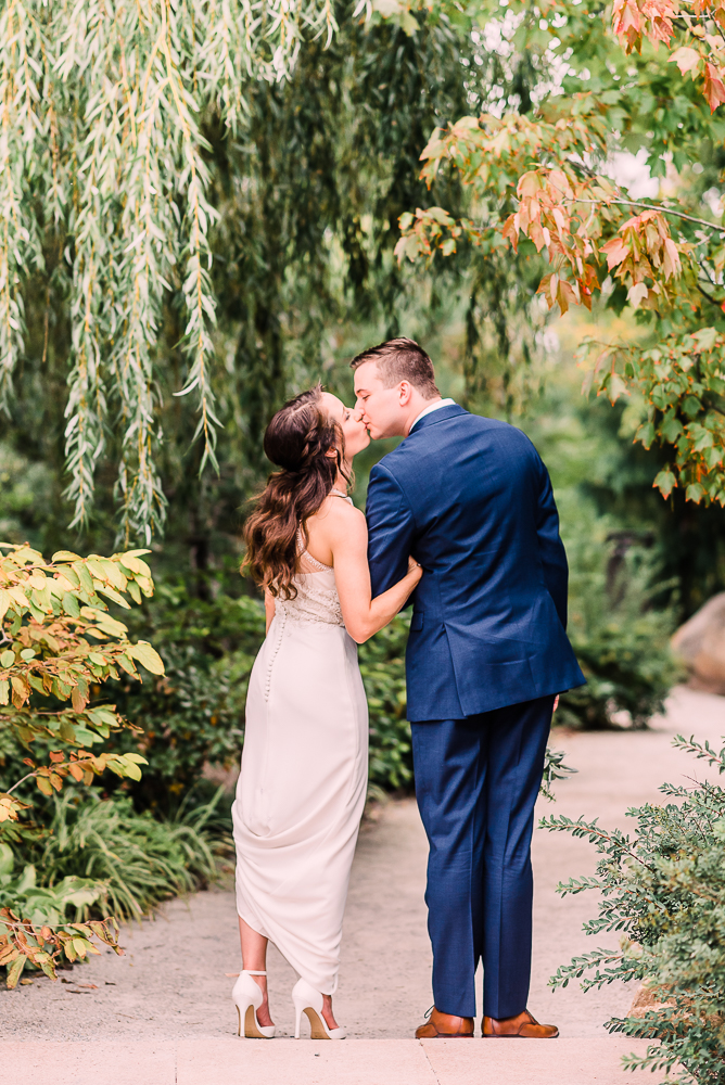 Bride and groom walking away from camera stop for a kiss at Fredrick Meijer Gardens by Grand Rapids wedding photographer Stephanie Anne 