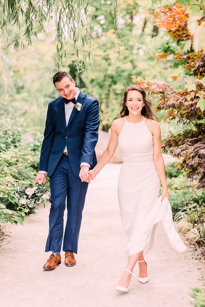 Bride and groom holding hands walking towards camera smiling at Fredrick Meijer Gardens by Grand Rapids wedding photographer Stephanie Anne