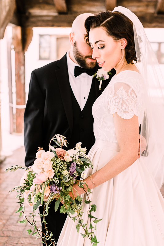 Bride and groom nose to nose bride holding soft pink white and purple bouquet groom in tx by grand rapids wedding photographer Stephanie Anne