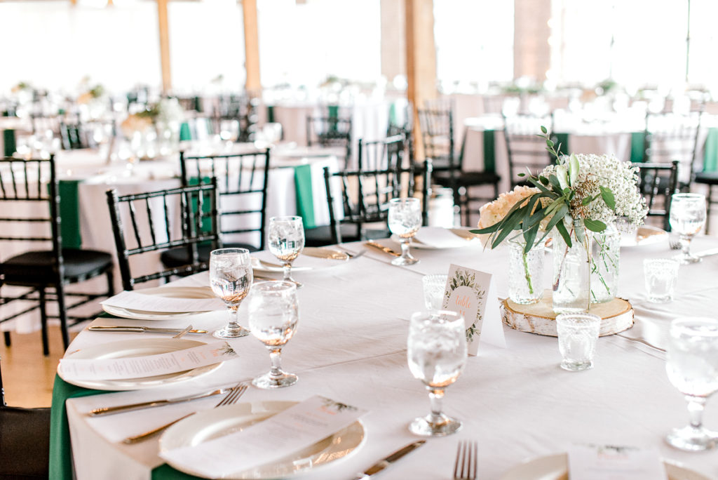 Wedding reception at Studio D2D in Grand Rapids white linens with dark green napkins and white dishes and peach and white flowers in center of table Stephanie Anne Photography