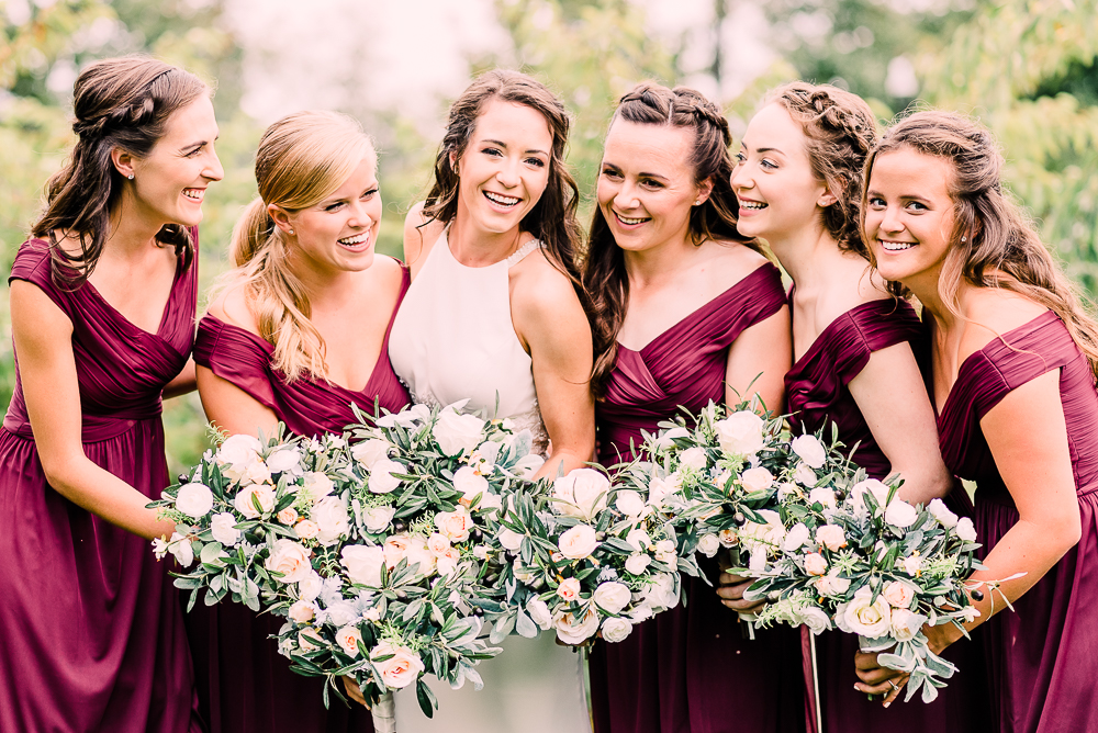 Bridal party in burgundy dresses and soft white flowers at Fredrick Meijer Gardens by Grand Rapids wedding photographer Stephanie Anne