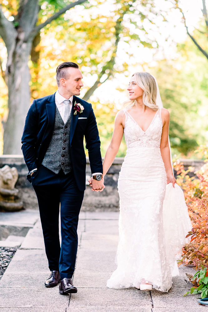 Bride and groom walking towards camera bride holding dress in one hand and grooms hand in other after intimate Michigan wedding by Grand Rapids Wedding photographer Stephanie Anne