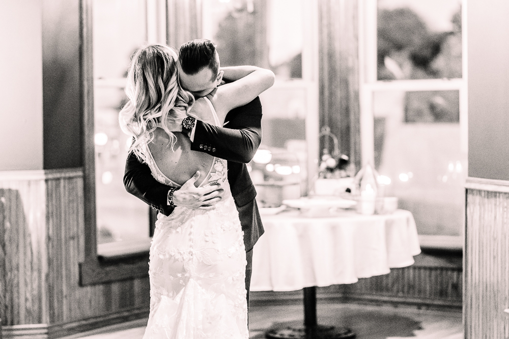 Bride and groom hugging at first dance together in black and white after intimate Michigan wedding ceremony by Grand Rapids Wedding photographer Stephanie Anne